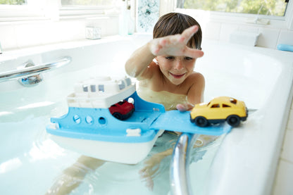 Boy in bath playing with Ferry Boat and mini cars