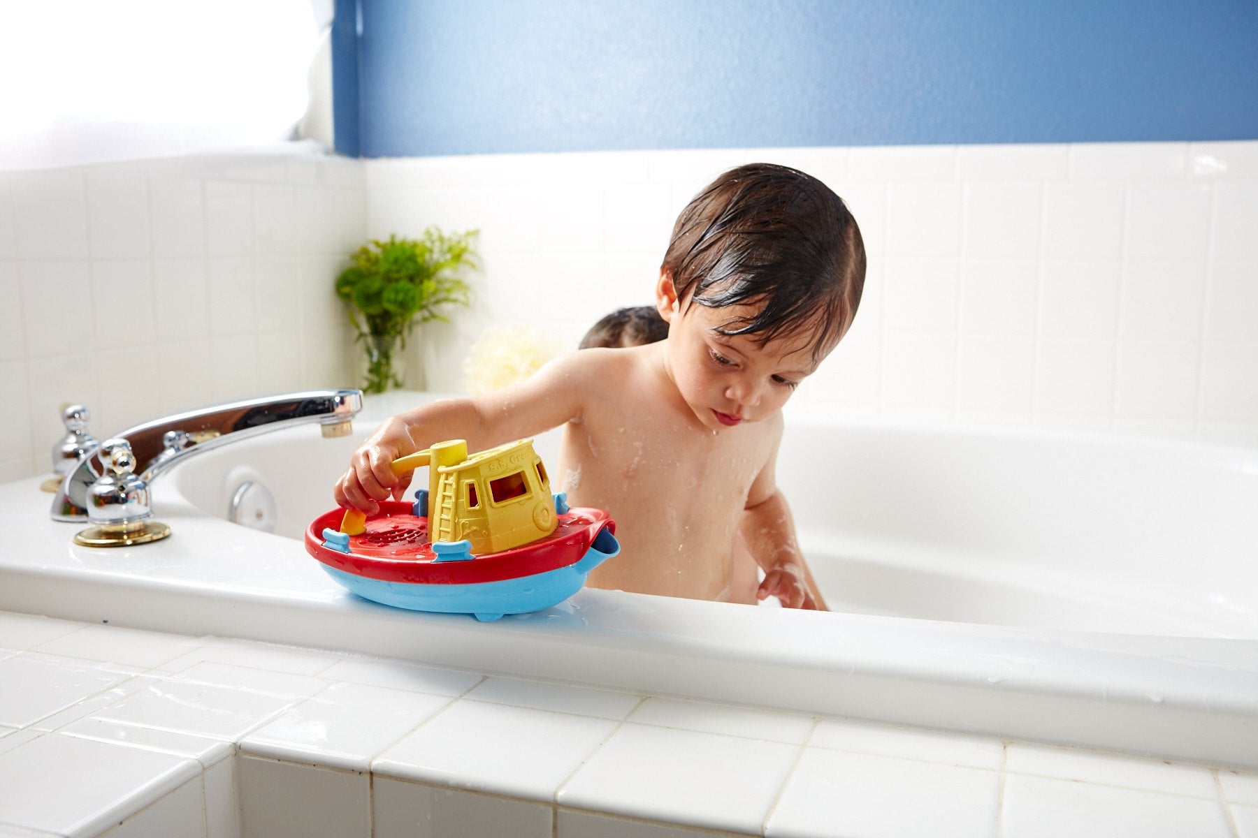Boy in bath playing with Yellow Tug boat