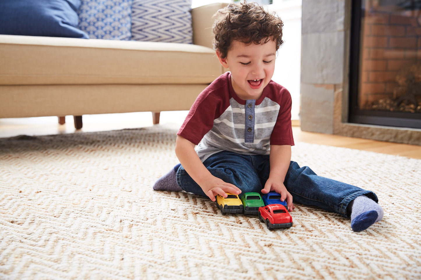Boy playing with yellow, green, blue, and red mini cars