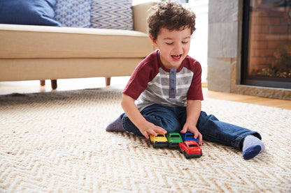 Boy playing with yellow, green, blue, and red mini cars