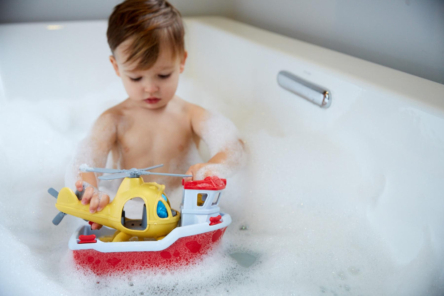 Boy in bath playing with Rescue Boat & Helicopter