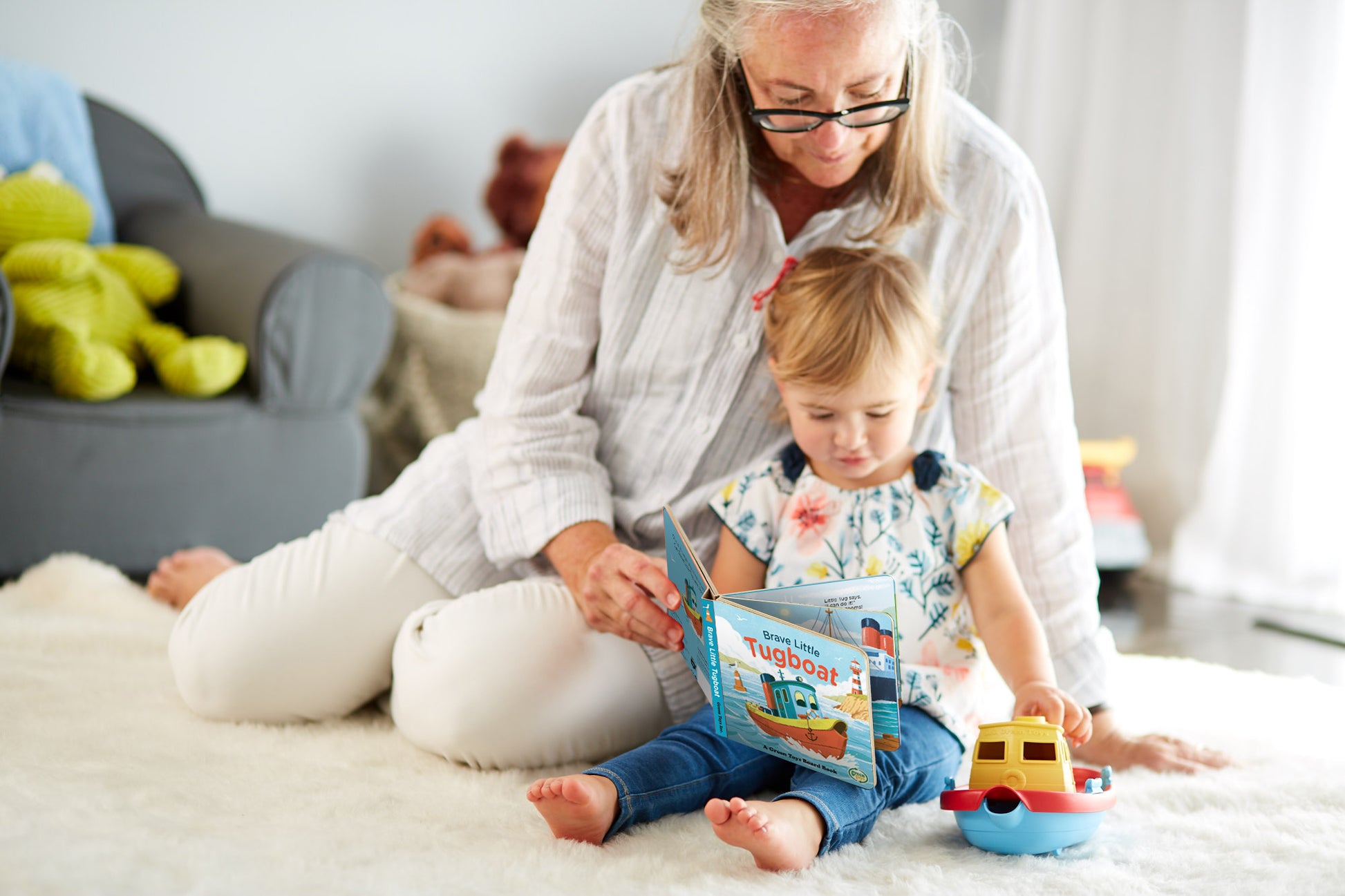Parent and child reading Board Book and playing with Tug Boat