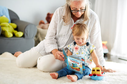 Parent and child reading Board Book and playing with Tug Boat
