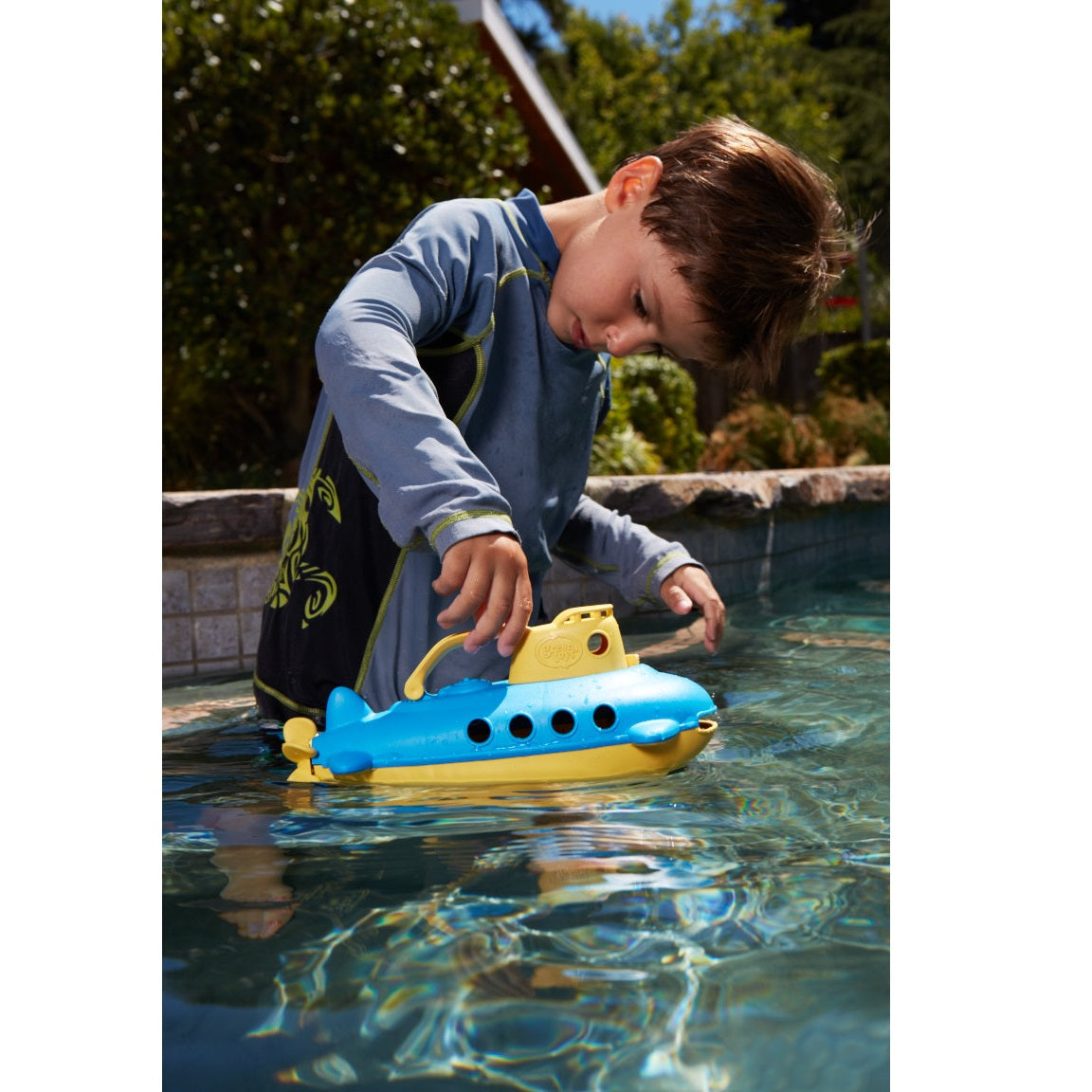 Boy in pool playing with Yellow Submarine